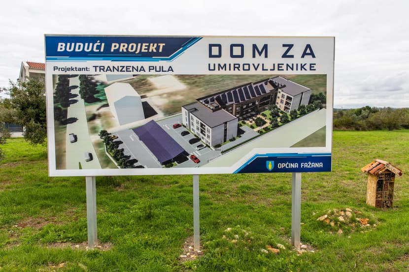 Tabla „Budući projekt: Dom za umirovljenike" na neizgrađenoj livadi u Fažani