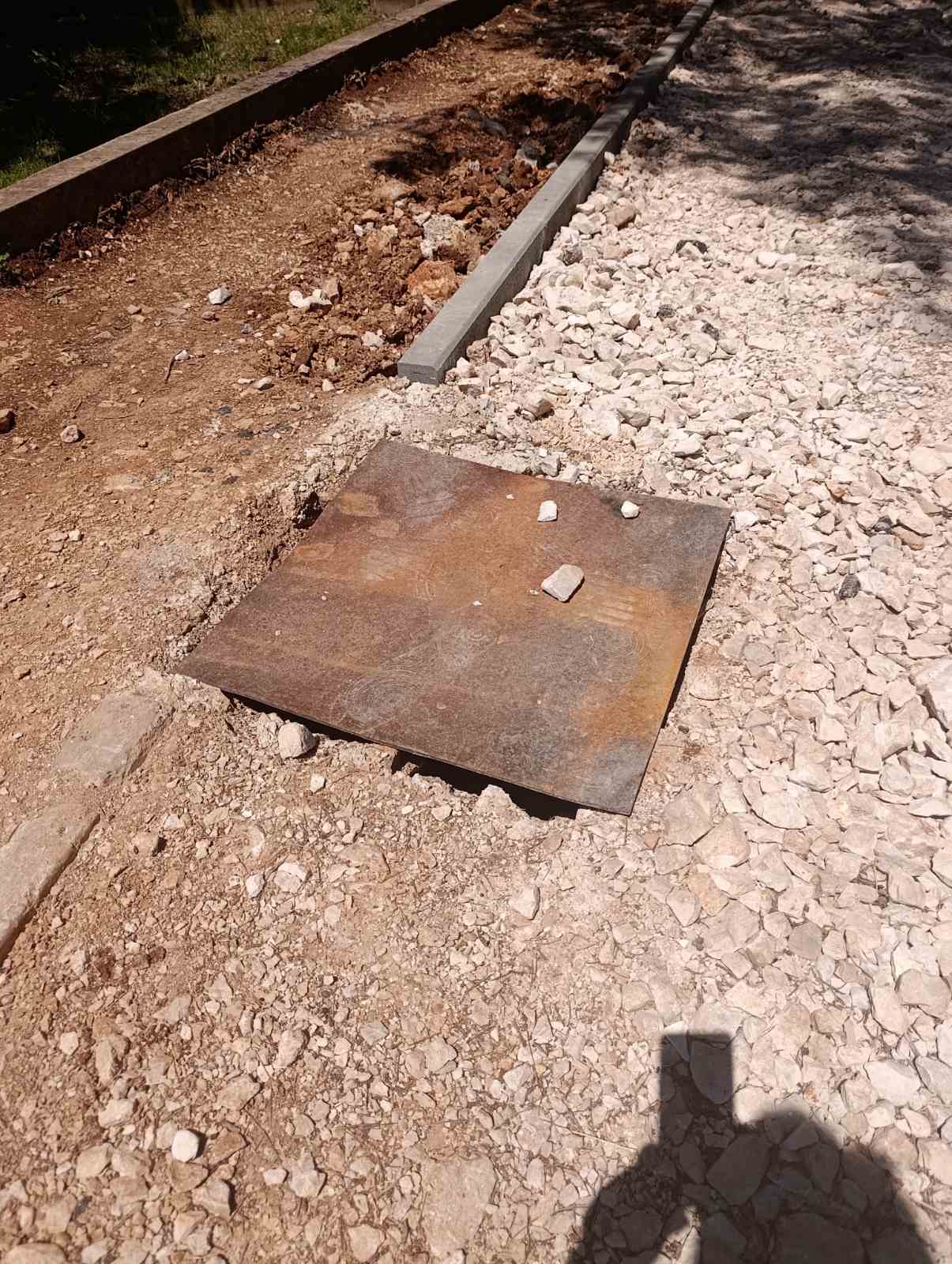 Metalna ploča preko otvorenog iskopa na pješačkoj stazi kraj škole