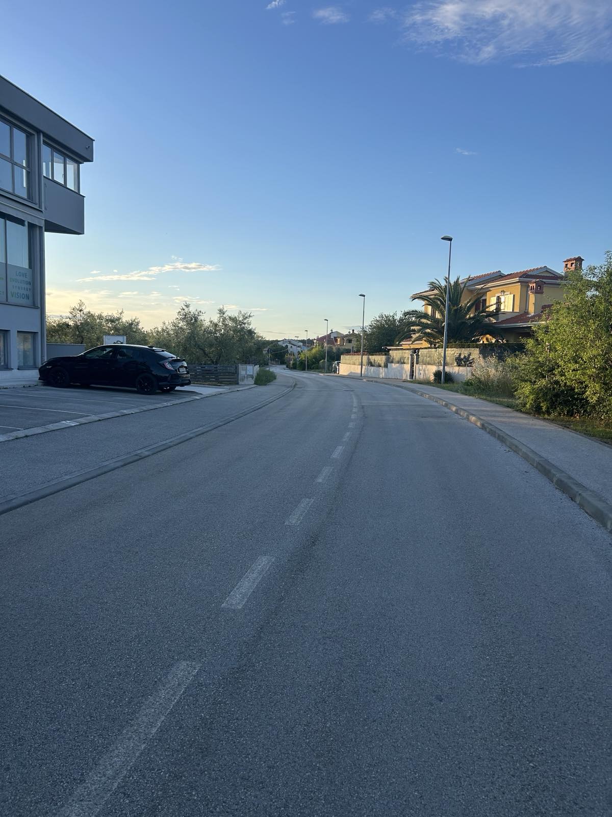 Dugi ravni potez Vlačićeve ulice bez usporivača prometa, s parkiranim vozilima uz rub